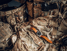 Tactical gear laid out on camouflage fabric